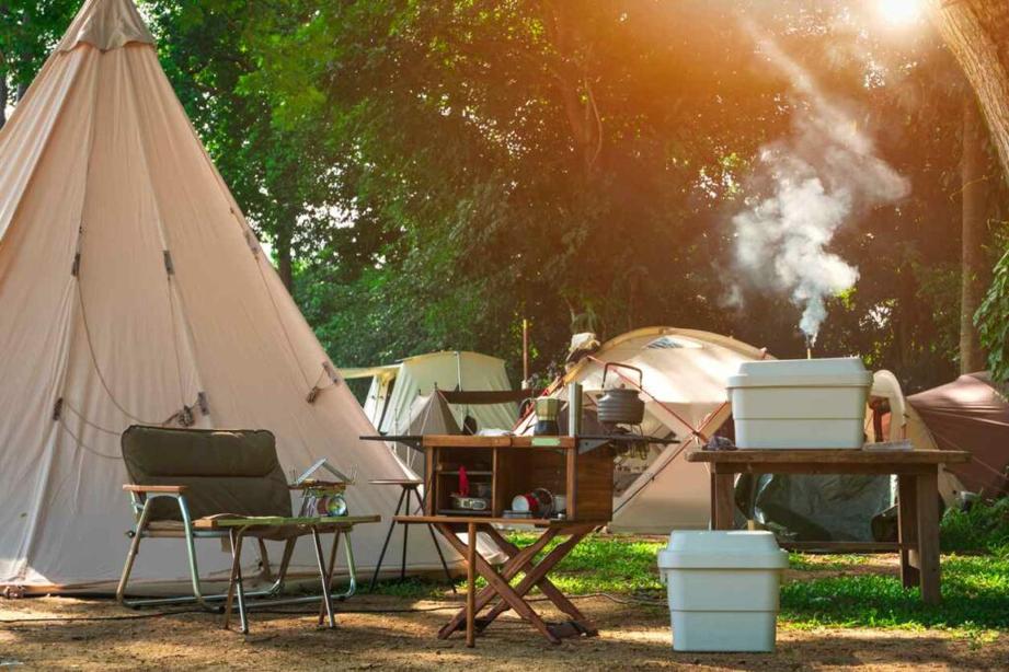 Camping chairs, coolers, and camp cooking supplies sitting outside of a series of tents