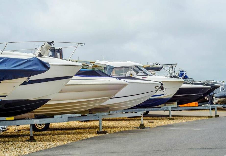 A line of boats are parked in outdoor, uncovered self storage