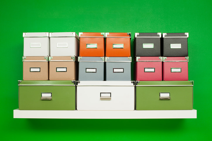 A shelf sits full of storage boxes against a bright green wall