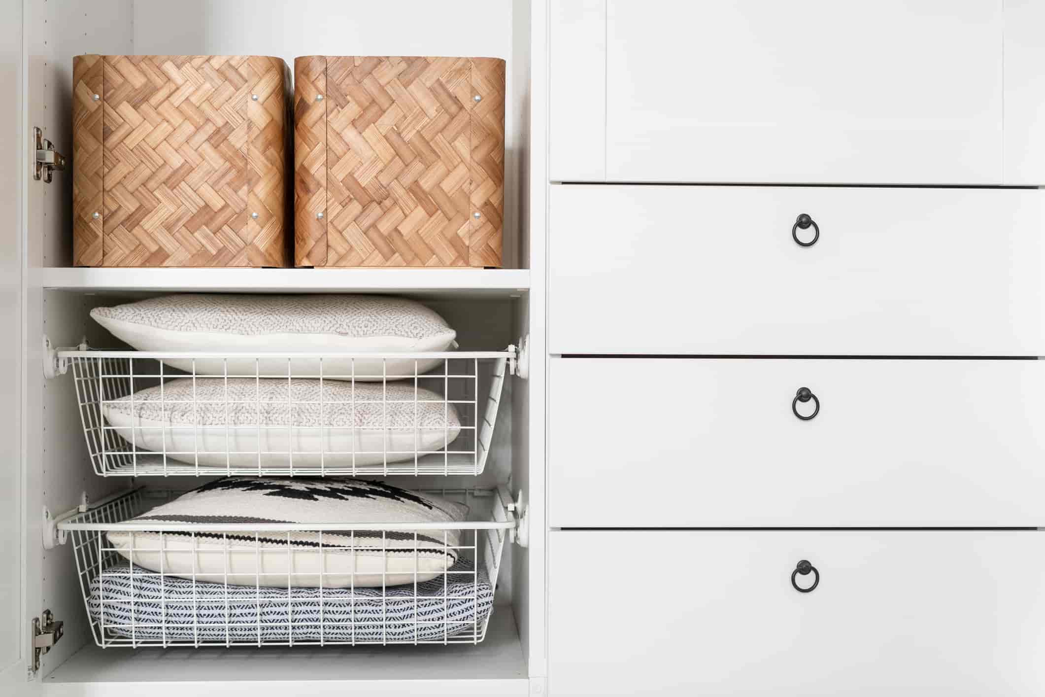 Shelving unit with baskets, pillows, and drawers.