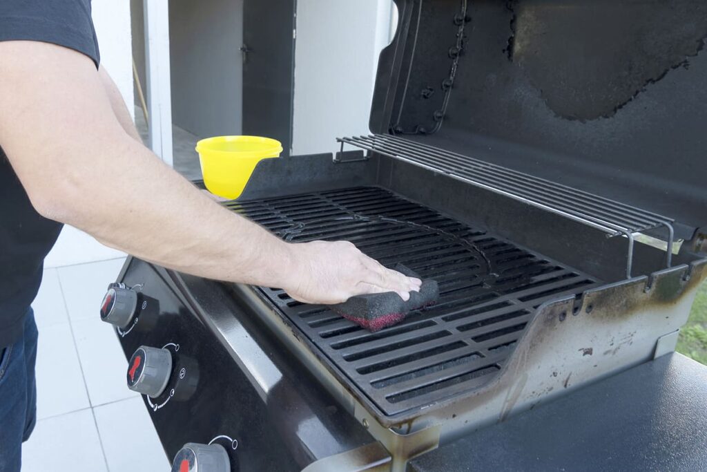 Man cleaning a grill.