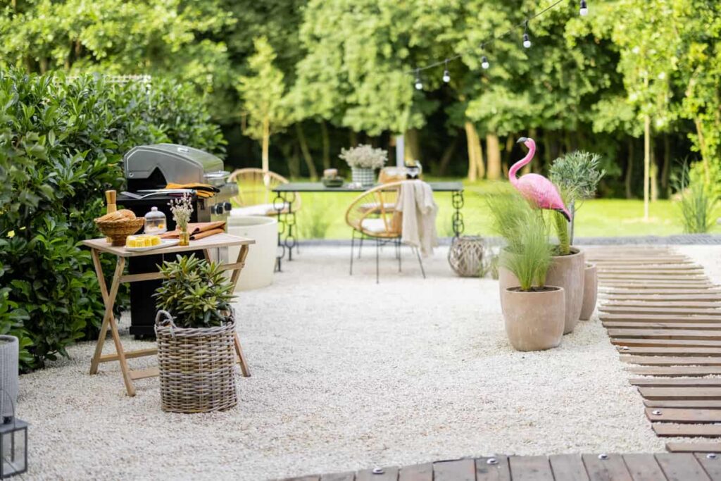 Barbecue and seating area decorated with plants, planters, hanging lights, and a plastic flamingo.