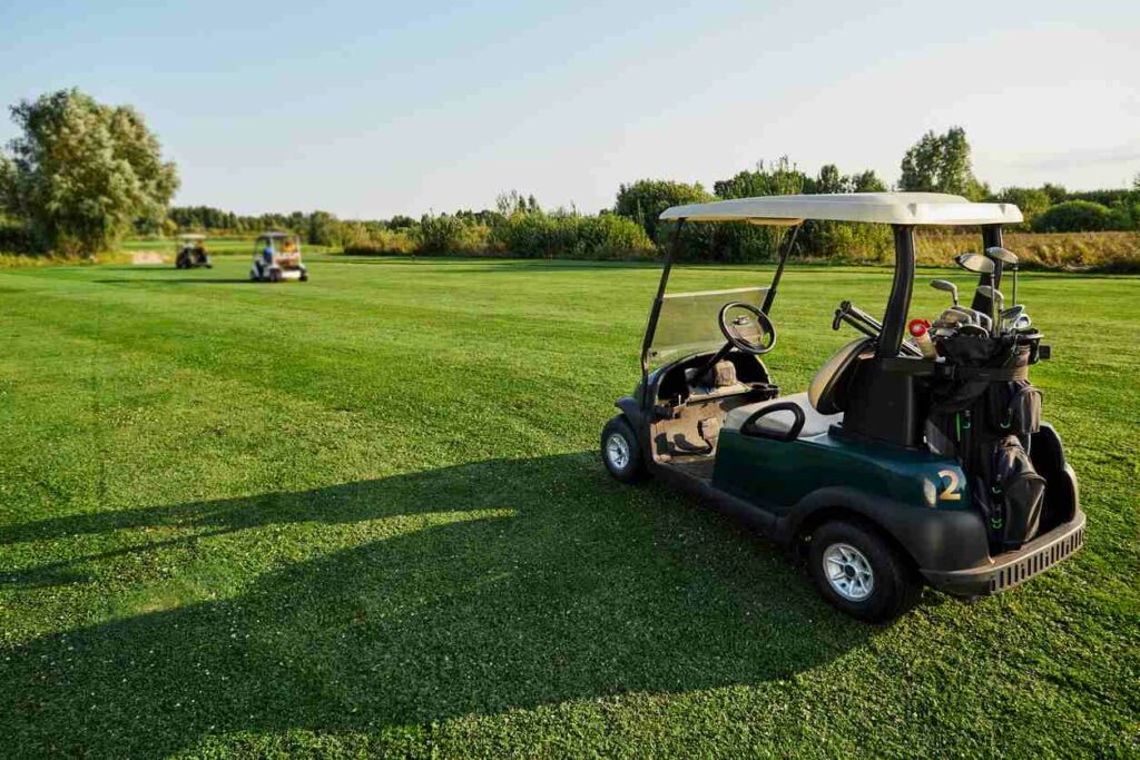 A few golf carts parked on a green golf course.