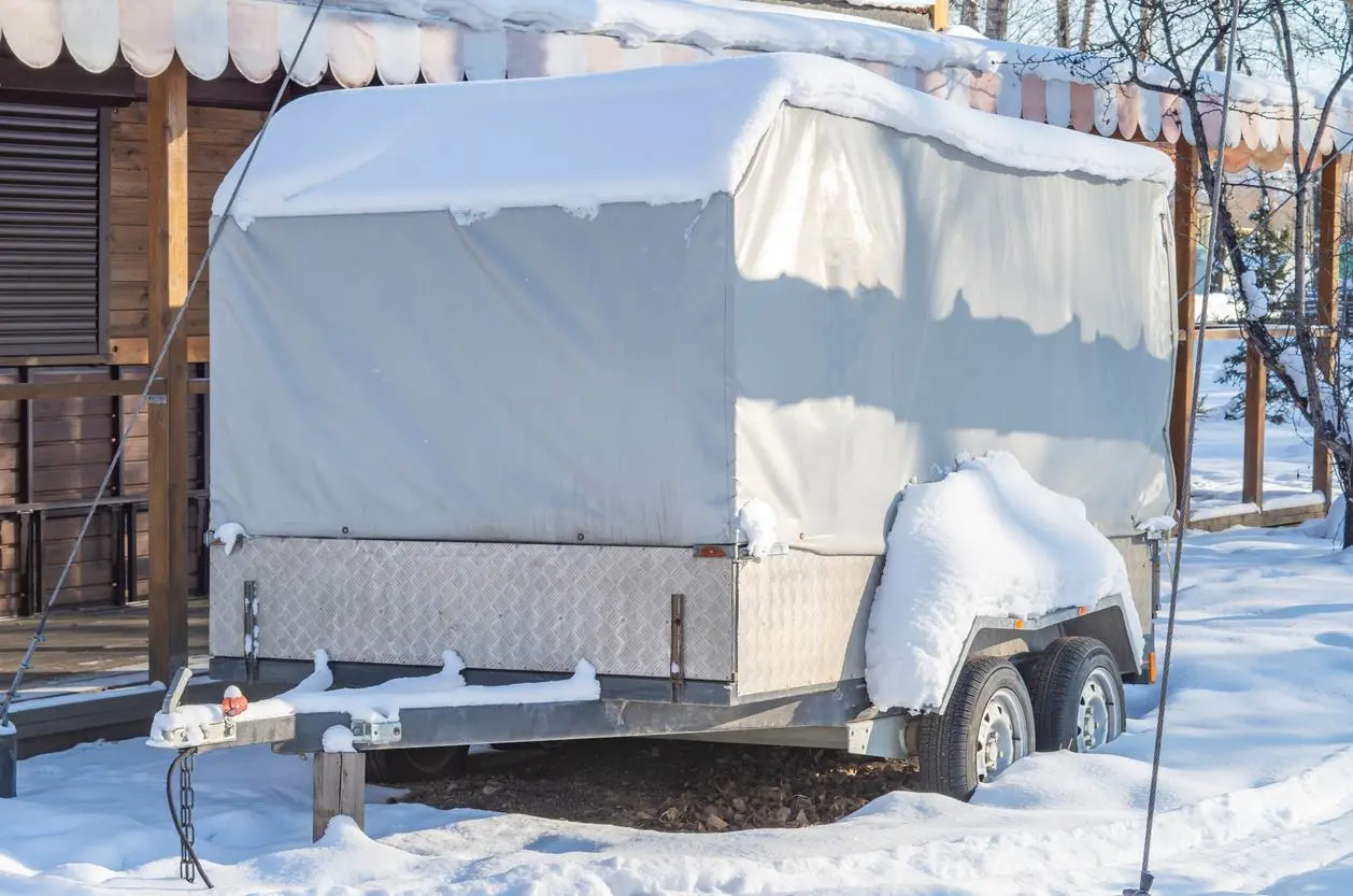 An RV with a cover over it protects it from the snow.