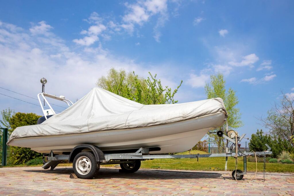 A boat in outdoor storage covered with a white protection tarp.